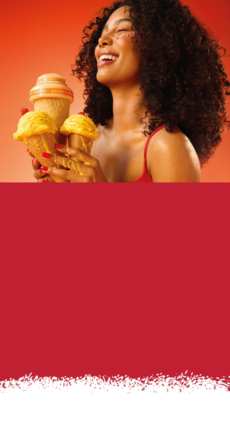 Mulher segurando dois frascos de produtos cosméticos nas mãos, com roupa salmão e com parede laranja ao fundo e ambiente em tons quentes
