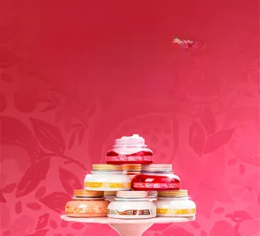 Pote de cremes hidratantes empilhados em formato de pirâmide sobre uma bandeja branca, com fundo vermelho decorado com ilustrações sutis de folhas e frutas.